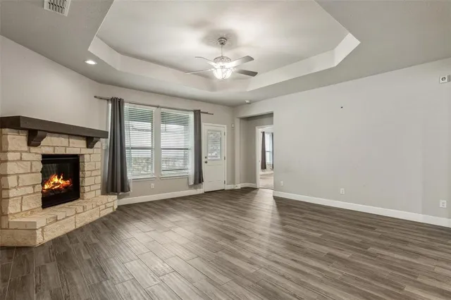 an empty room with wooden floor fireplace and windows