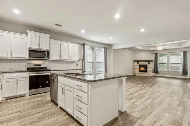 a kitchen with granite countertop a stove sink and microwave