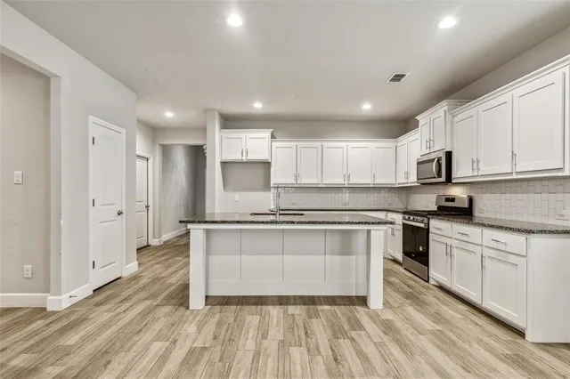 a large kitchen with stainless steel appliances granite countertop a stove and a sink