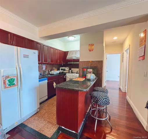 a kitchen with stainless steel appliances granite countertop a refrigerator a sink dishwasher a stove with wooden cabinets and wooden floor