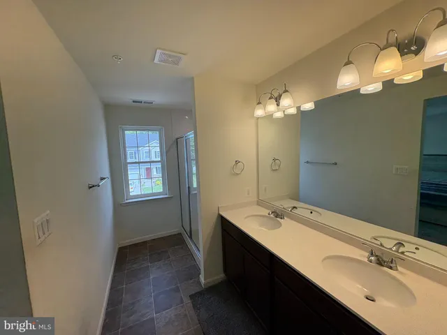 a spacious bathroom with a double vanity sink a large mirror and a shower