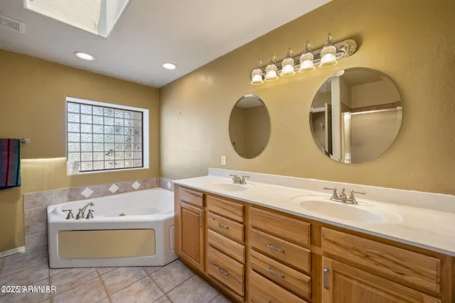 a spacious bathroom with a double vanity sink mirror and bathtub