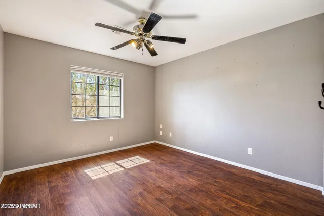 an empty room with wooden floor fan and windows
