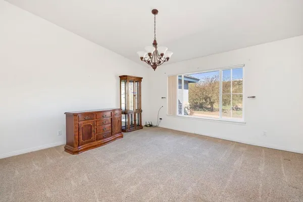 an empty room with chandelier fan and windows