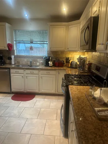 a kitchen with granite countertop a stove top oven microwave and cabinets