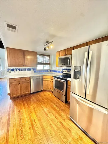a kitchen with a refrigerator a stove top oven and cabinets
