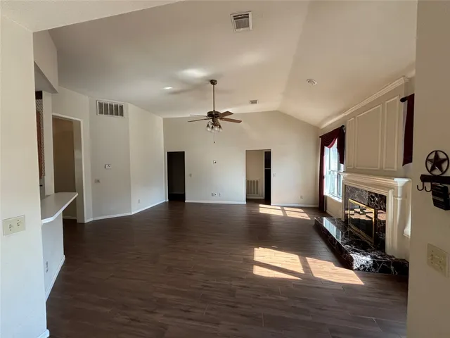 a view of an empty room with wooden floor and a fireplace