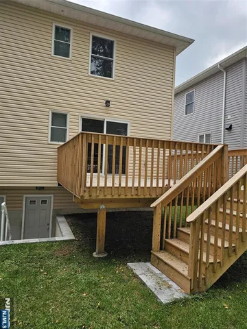 a view of house with deck and a yard