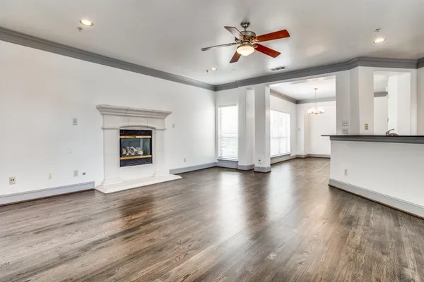 an empty room with wooden floor a ceiling fan a fireplace and windows