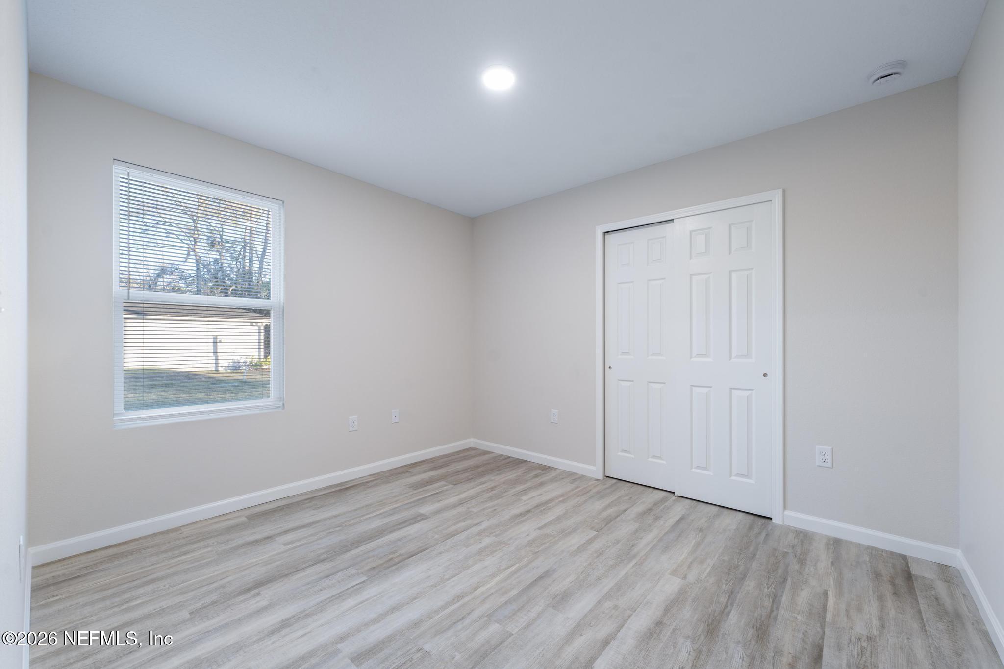 7581 Dove Road Jacksonville, FL 32219 - Photo 26 of 32 an empty room with wooden floor and windows