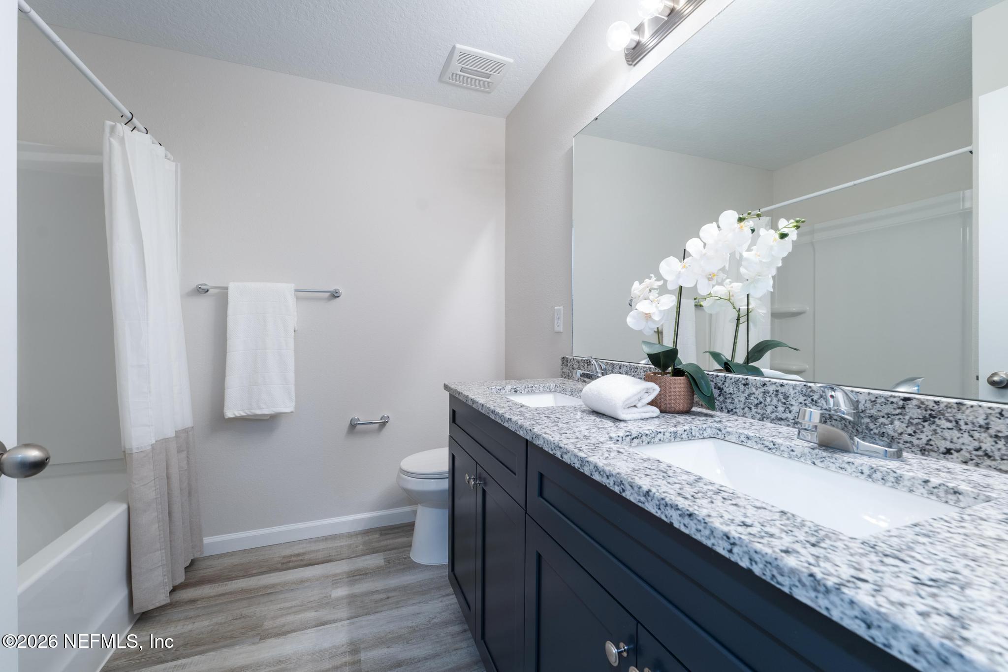 7581 Dove Road Jacksonville, FL 32219 - Photo 27 of 32 a bathroom with a granite countertop sink a toilet and mirror