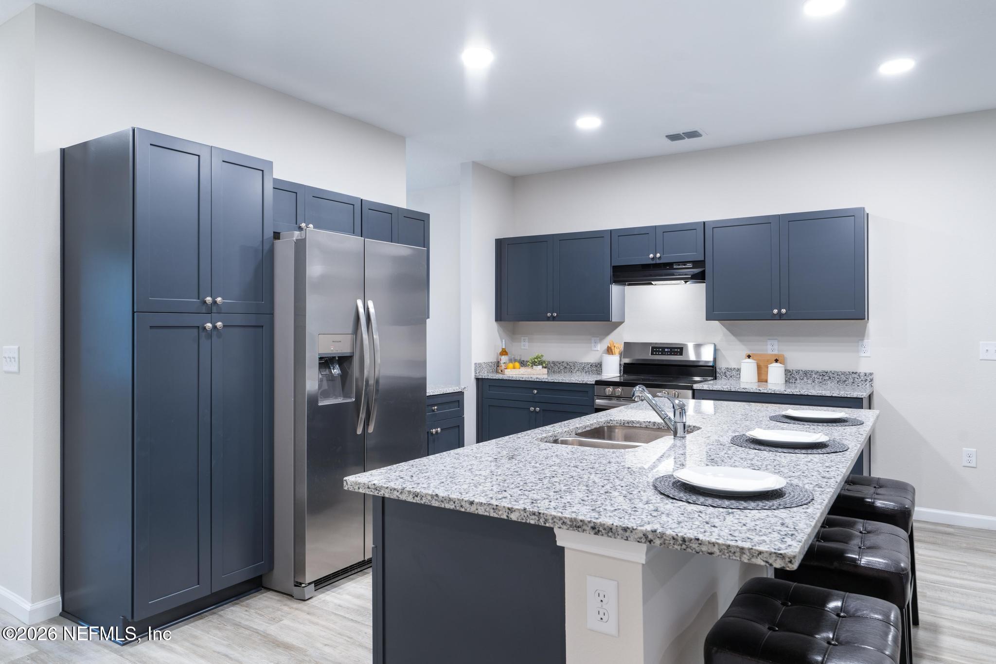 7581 Dove Road Jacksonville, FL 32219 - Photo 9 of 32 a kitchen with kitchen island granite countertop stainless steel appliances and wooden cabinets
