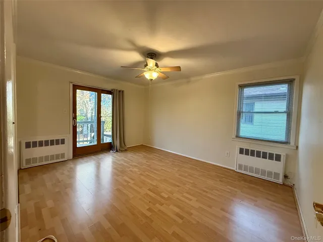 a view of an empty room with window and wooden floor