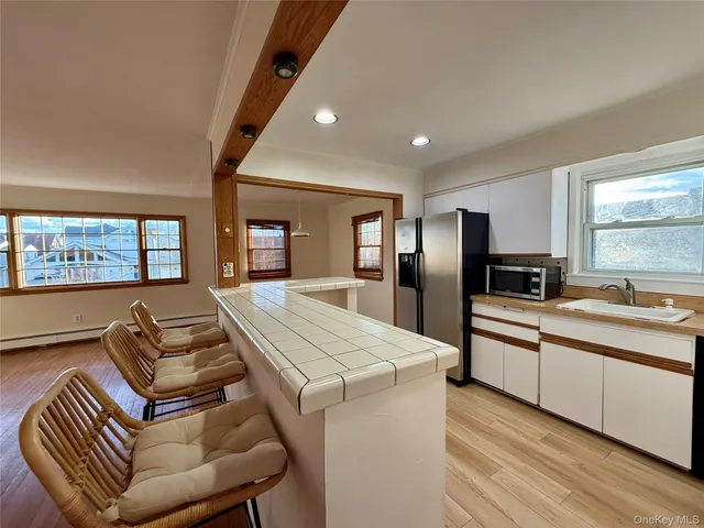 a kitchen with stainless steel appliances granite countertop a refrigerator a sink dishwasher a dining table and chairs with wooden floor