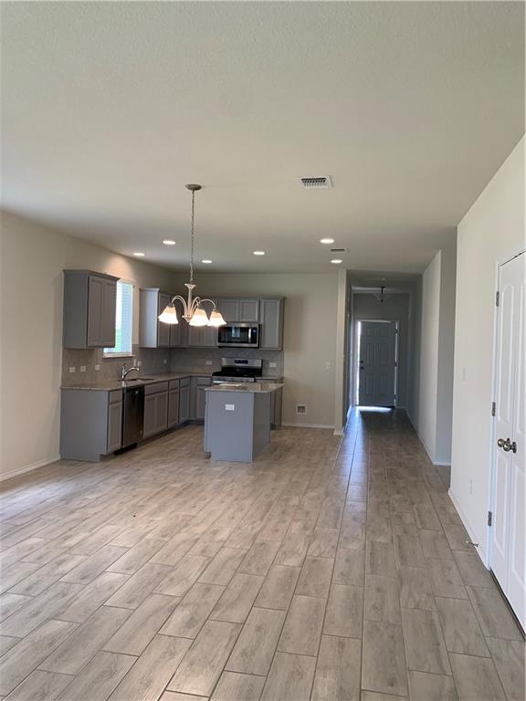 1229 Cliffbrake Way Georgetown, TX 78626 - Photo 8 of 24 a view of a kitchen with kitchen island a sink wooden floor and a refrigerator