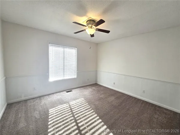 an empty room with chandelier fan and windows