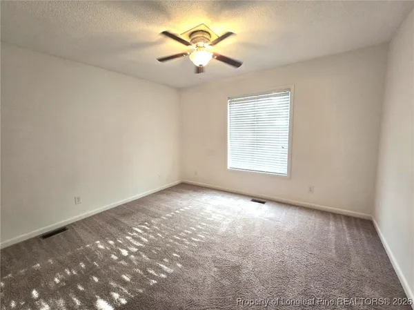 an empty room with windows and ceiling fan