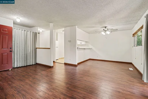a view of an empty room with wooden floor and a window