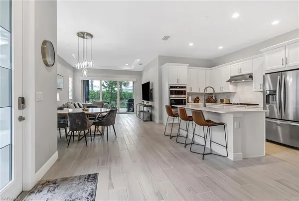 a kitchen with stainless steel appliances a dining table chairs stove refrigerator and cabinets