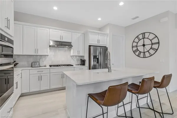 a kitchen with stainless steel appliances a stove a sink cabinets and a refrigerator