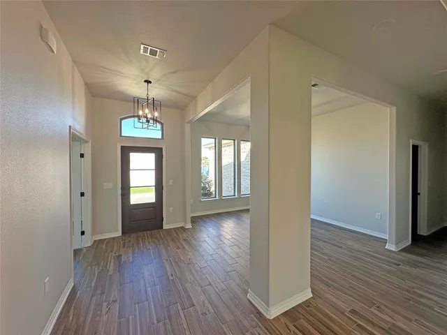 en view of an empty room with wooden floor and a window