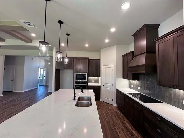 a large kitchen with stainless steel appliances kitchen island granite countertop a large counter top a stove and a refrigerator