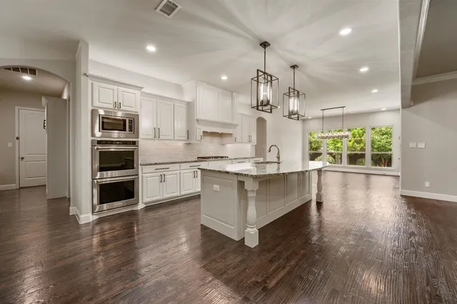 a large kitchen with granite countertop a white stove top oven and white cabinets