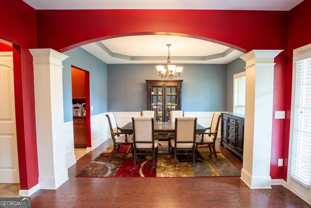 a dining room with furniture a chandelier and wooden floor