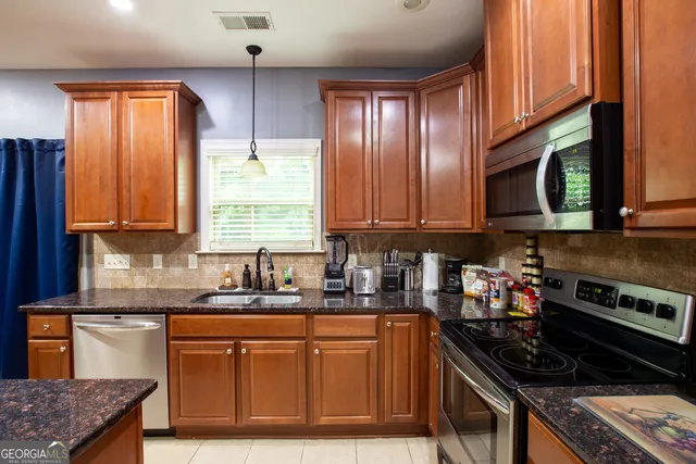 a kitchen with stainless steel appliances granite countertop a stove a sink dishwasher and a microwave oven with cabinets