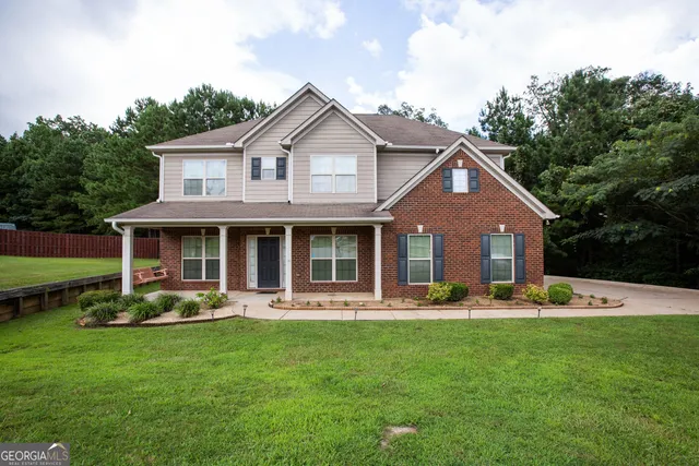 a front view of a house with garden and trees