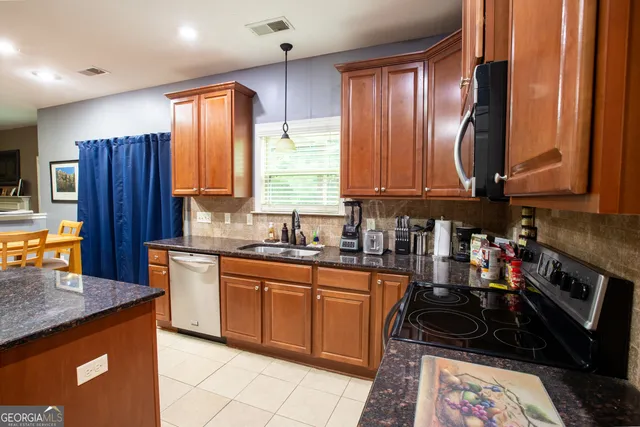 a kitchen with stainless steel appliances granite countertop a sink a stove a refrigerator and cabinets