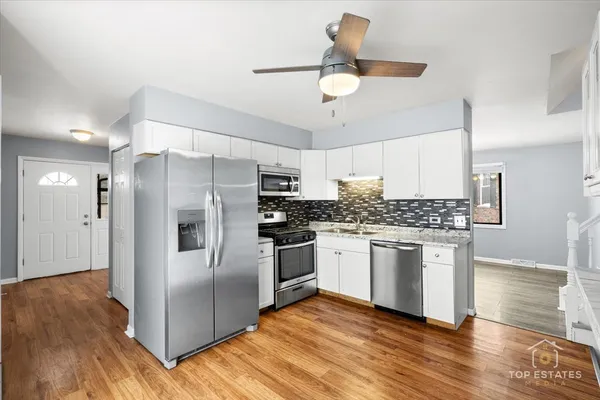 a kitchen with stainless steel appliances granite countertop a refrigerator and a stove top oven