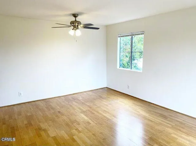an empty room with a window and a ceiling fan