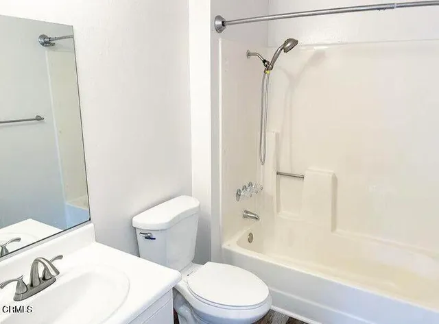 a white toilet sitting next to a bath tub
