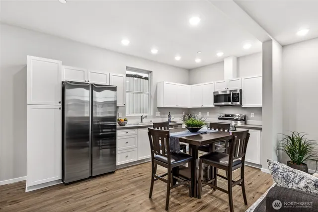 a kitchen with stainless steel appliances a dining table chairs refrigerator and microwave