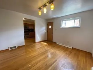 a view of an empty room with window and wooden floor