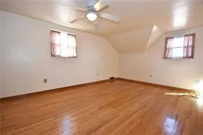 an empty room with wooden floor chandelier fan and windows