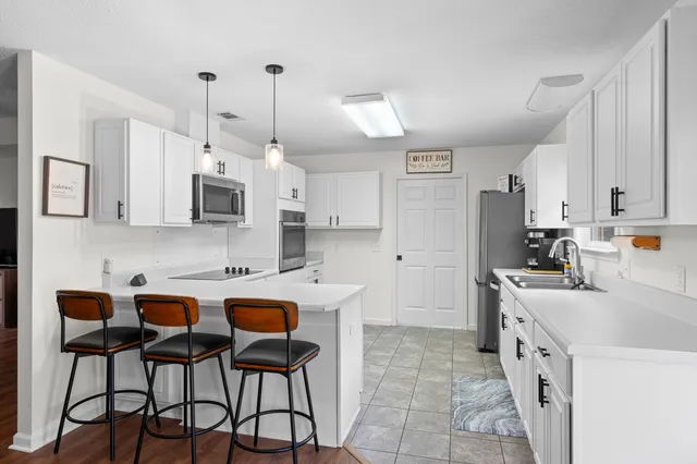 a kitchen with cabinets stainless steel appliances and wooden floor