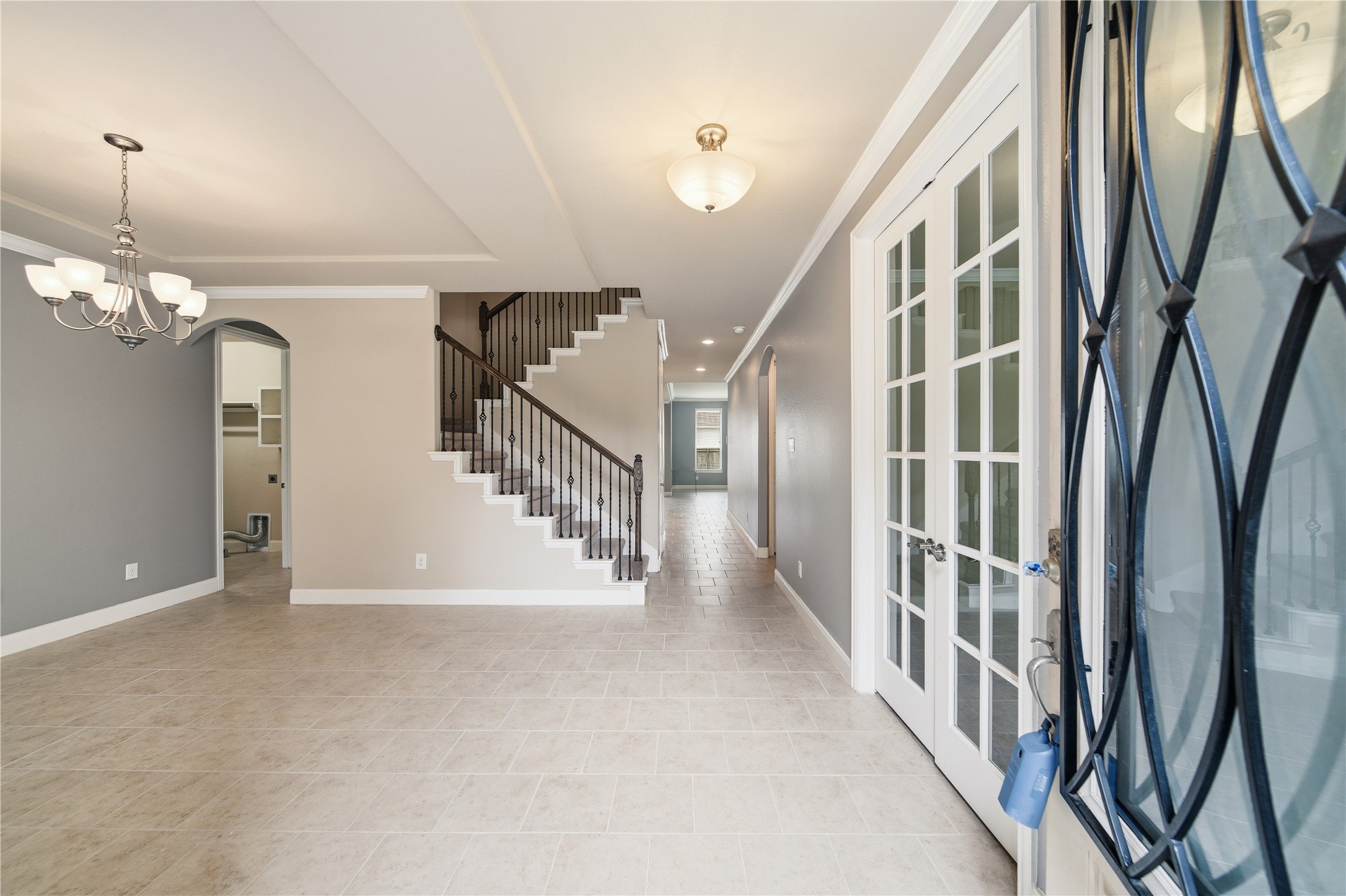 5303 Mesquite Willow Lane Rosharon, TX 77583 - Photo 2 of 32 Tile seamlessly invites you in with functionality and convenience. This home features a bright entryway and formal dining area with tile flooring, a modern chandelier, and French doors which lead into the office area. A staircase with elegant railings creates a welcoming and spacious atmosphere.