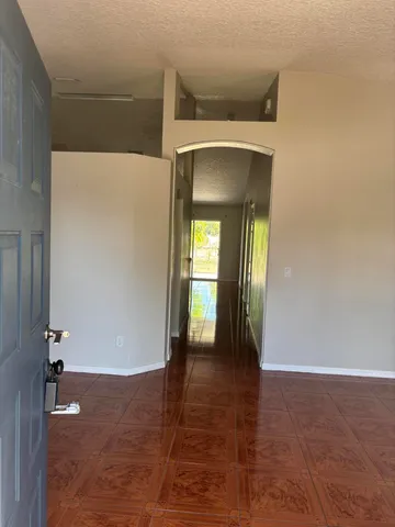 a view of a hallway with wooden floor and a bathroom
