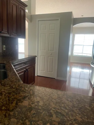 a view of kitchen and empty room with wooden floor