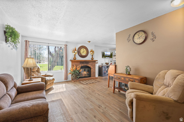 1120 Canyon Road, Unit 38 Ogden, UT 84404 - Photo 5 of 24 Living room featuring light wood-type flooring, a textured ceiling, and a brick fireplace
