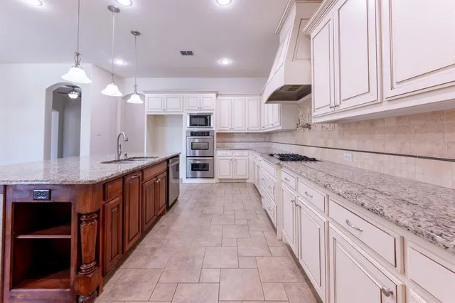 a large kitchen with stainless steel appliances kitchen island granite countertop a sink and cabinets