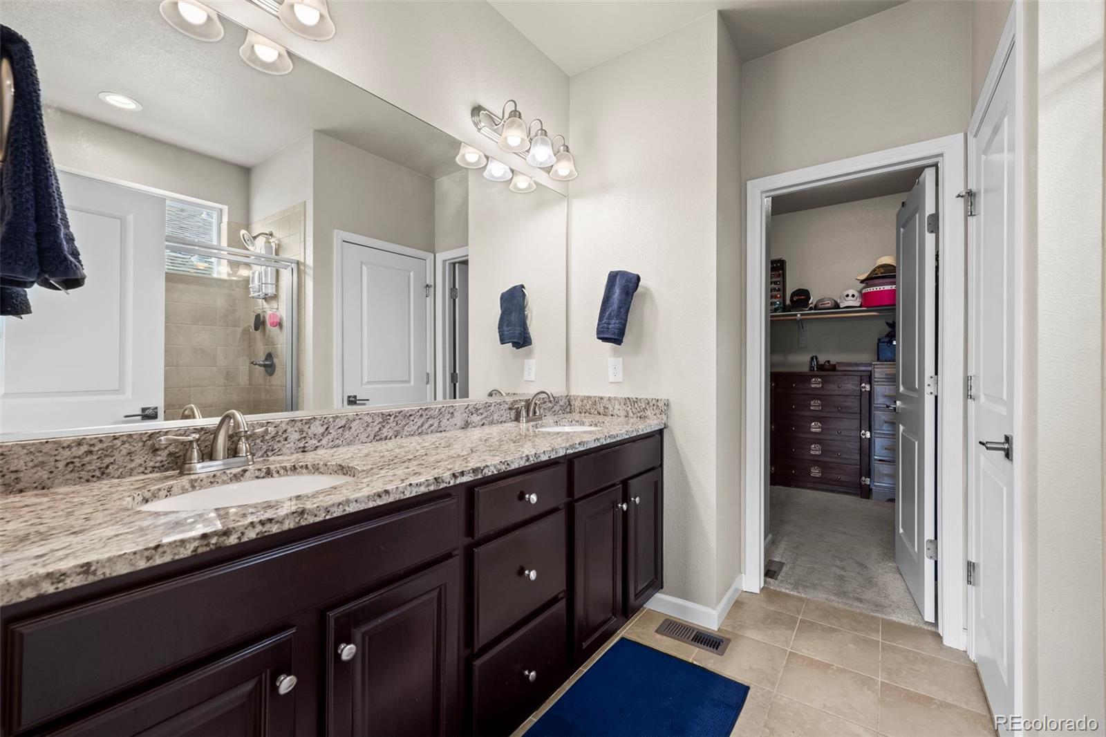 593 Country Road Berthoud, CO 80513 - Photo 11 of 34 a bathroom with a granite countertop sink a mirror and a shower