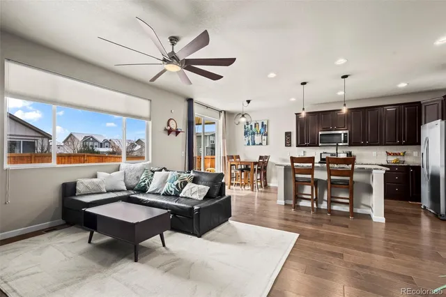 a living room with furniture kitchen view and a wooden floor