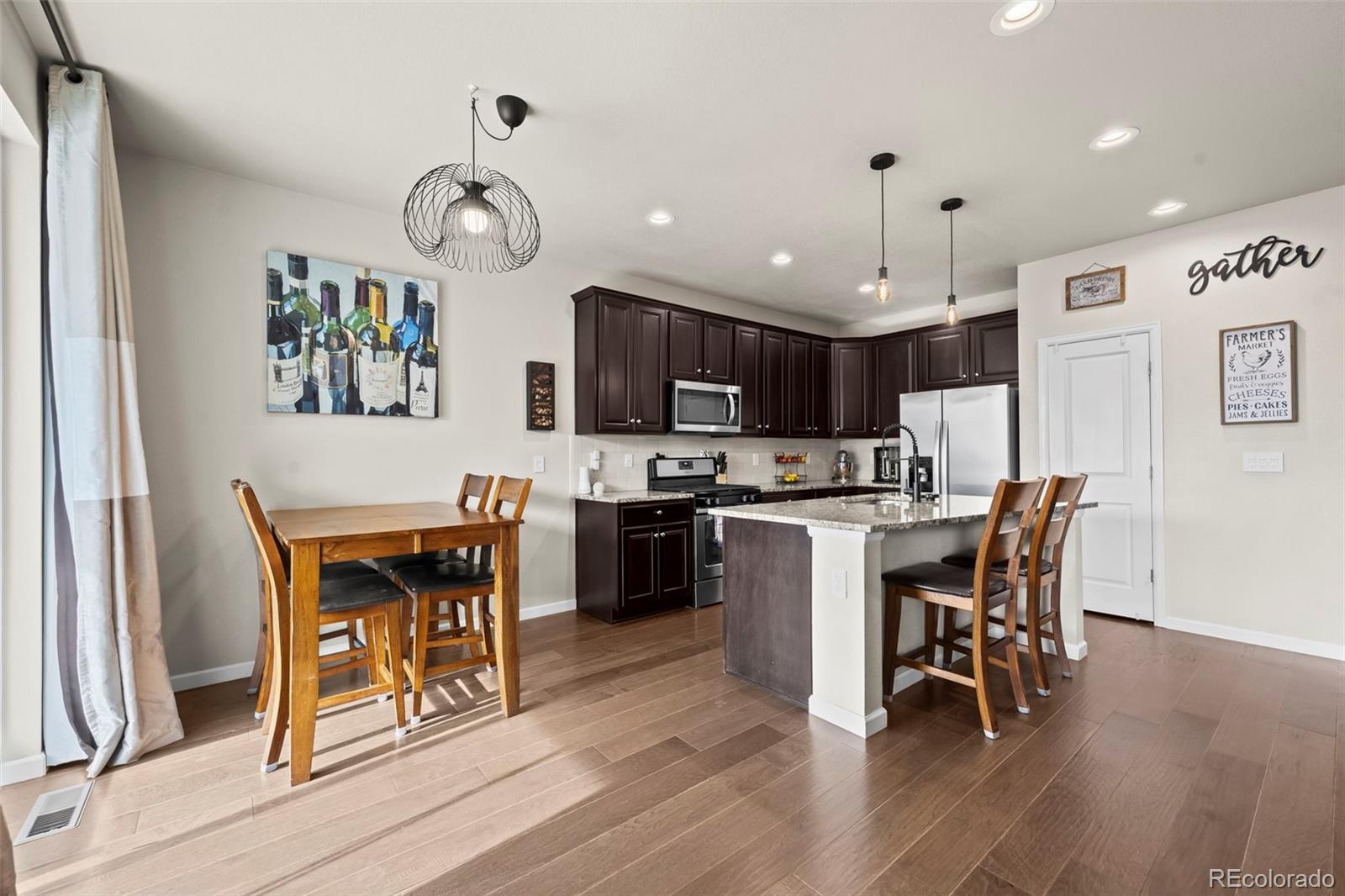 593 Country Road Berthoud, CO 80513 - Photo 5 of 34 a kitchen with stainless steel appliances granite countertop a stove top oven a refrigerator a sink and a dining table with wooden floor