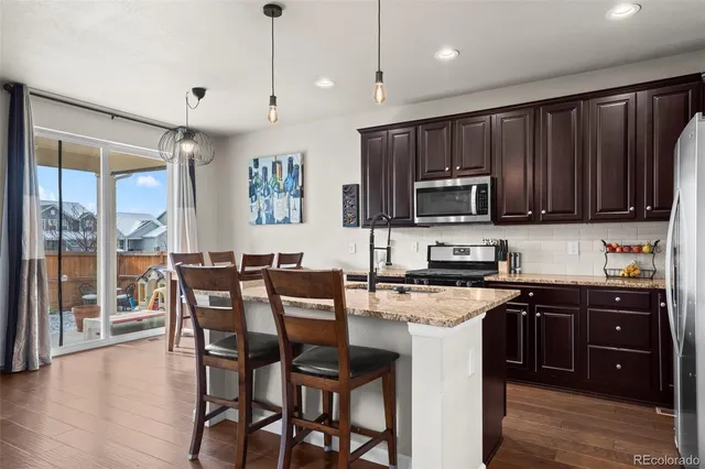 a kitchen with a stove a sink a microwave a dining table and chairs