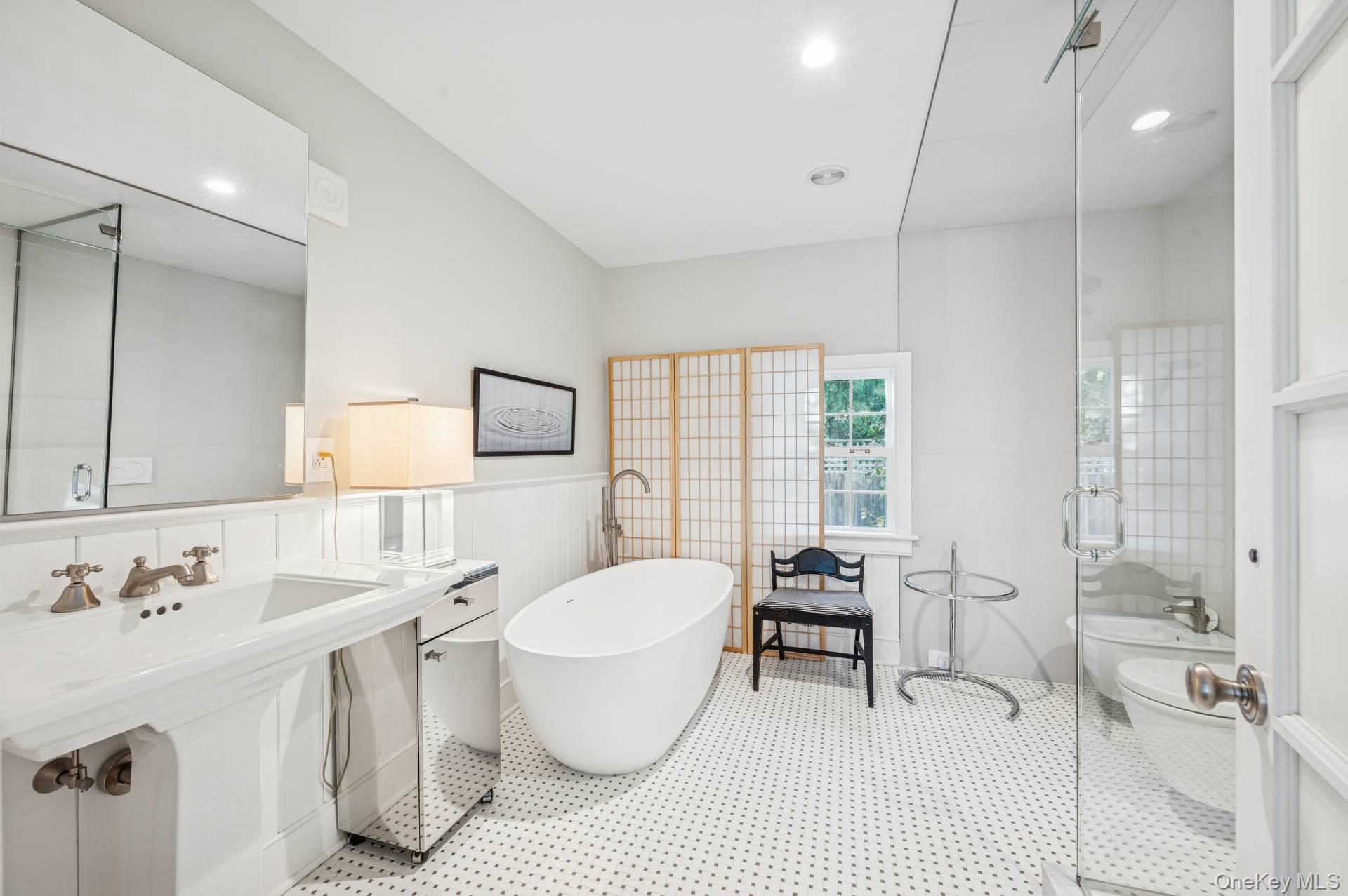 94 Post Lane Southampton, NY 11968 - Photo 12 of 34 a spacious bathroom with a double vanity sink a mirror and a bathtub