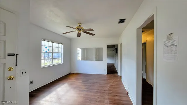 a view of an empty room with a window and wooden floor