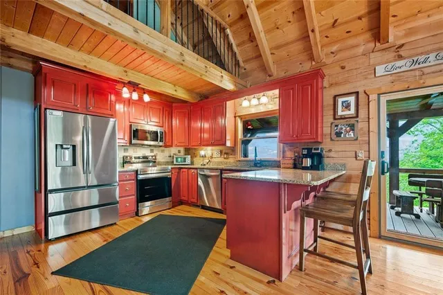 a kitchen with stainless steel appliances granite countertop a refrigerator a stove and a wooden floors